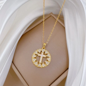 Detailed macro view of a gold-tone heart-shaped pendant with a cross and inlaid diamonds
