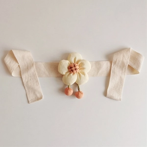 Detailed shot of beige fabric floral curtain tieback with pink accents on flat surface