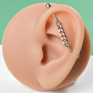 Detail of stainless steel industrial barbell earring with cross chain on ear model