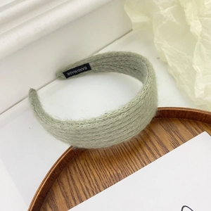 Detail of light green knitted headband with soft mohair texture and hand made label