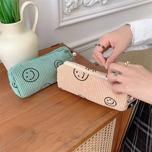 Detail view of corduroy cosmetic pouch with smiley face embroidery and metal zipper closure