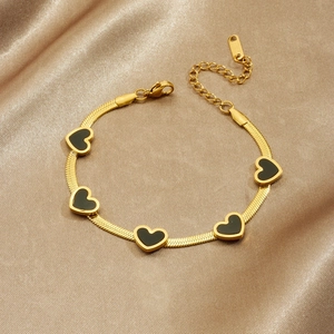 Gold plated snake chain bracelet with five black heart pendants on champagne silk background