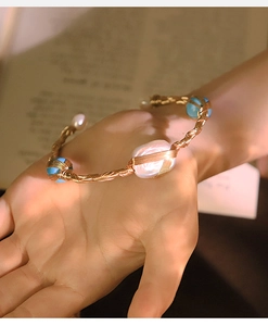 Close-up of hand-woven bracelet featuring baroque pearls and blue beads on wire