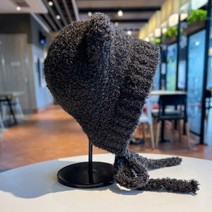 Dettaglio del cappello in maglia grigio scuro con orecchie da orso e lacci morbidi