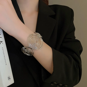 Detail of silver wavy spiral bangle featuring a triple swirl design on a model's wrist