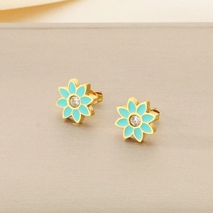 Gros plan de boucles d'oreilles fleurs en émail vert menthe avec zircon central