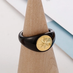 Retro black resin ring with a gold octagonal star emblem on a wooden display cone