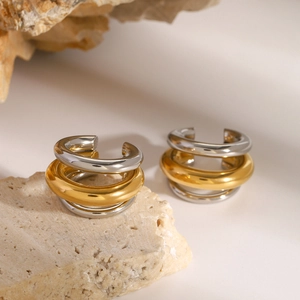 Boucles d'oreilles trois couches bicolores or et argent posées sur une pierre naturelle
