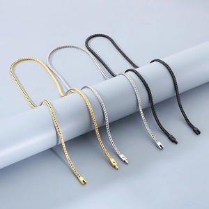 Detail of woven wheat chains in gold, silver, grey, and black on a cylinder display stand