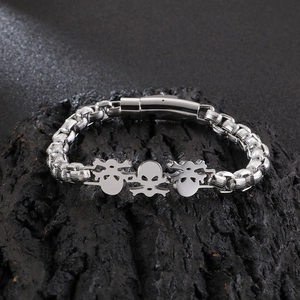Macro detail of silver skull charms and thick punk chain on a dark stone background