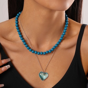 Detail showing double-layered necklace with turquoise beads and blue heart pendant