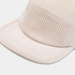 Close-up of beige corduroy fabric texture and fine stitching on the five-panel cap