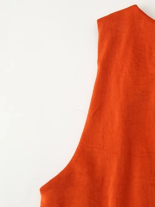 Detailed macro view of orange satin fabric texture and side pleats on the dress
