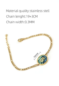 Detailed view of golden stainless steel bracelet with an S letter shell pendant