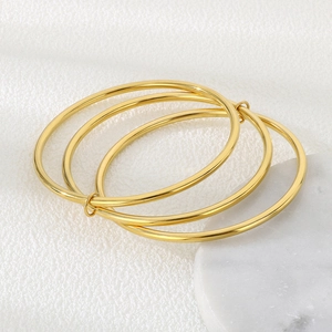Detailed view of three interlocked 3mm gold stainless steel bangles on white fabric