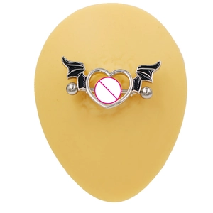 Macro view of silver heart nipple ring with black wings on a yellow mannequin model
