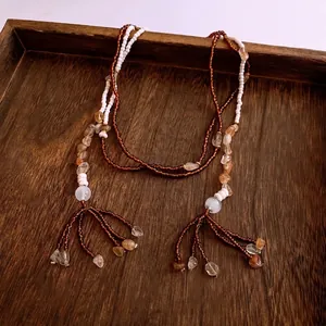 Ethnic bohemian beaded necklace with tassels and irregular stones on wooden tray