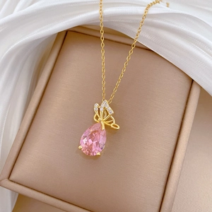 Detailed close-up of a butterfly pendant with a pink water-drop gemstone on a gold chain