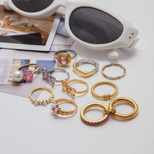 Flat lay of 10 gold and silver rings with pink crystals, pearls, and butterfly charms