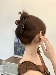 Detail view of a dark coffee translucent bow hair clip styled on a model's half-up hair