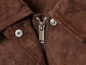 Macro detail of brown suede jacket with silver metal zipper and button closure