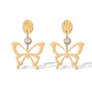 Macro detail of gold-plated butterfly earrings featuring hammered disks and elegant pearls