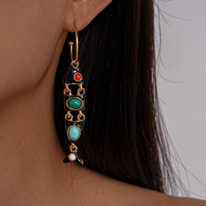Close-up of vintage enamel fish bone earrings with colorful stones on model ear
