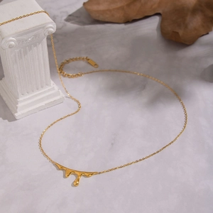 Detail of 18K gold-plated irregular fluid teardrop pendant on minimalist stone stand