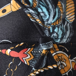 Detailed close-up of Baroque pattern on black satin baseball cap with golden embroidery