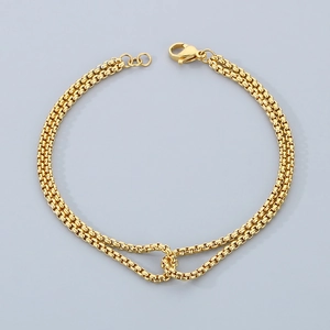 Detail of gold double-layer chain bracelet with adjustable lobster clasp on grey background