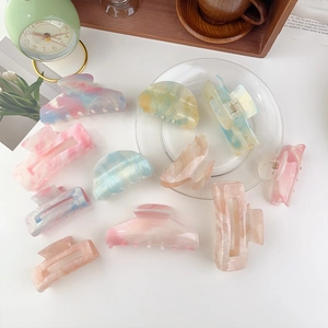 Assorted acetate hair claws in iridescent colors and marbled patterns on a white desk