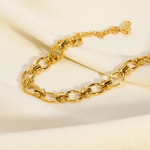Detailed macro view of 18K gold plated chain links on elegant white satin fabric