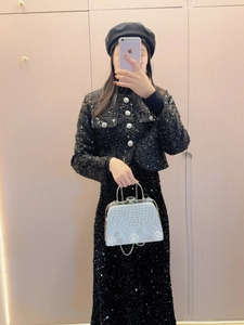 Silberne Strass-Abendtasche gehalten von einem Model in schwarzem Paillettenkleid