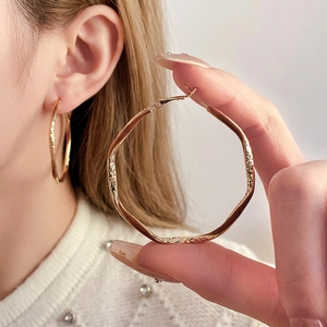 Irregular large golden hoop earrings with hammered texture and minimalist geometric design