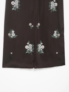 Détail de la broderie florale et des perles faites main sur une jupe sombre