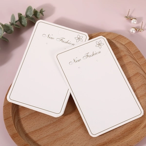 Elegant white jewelry display cards with gold foil logo on a minimalist wooden tray