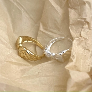 Detail shot of gold and silver S925 sterling silver bow rings on textured paper