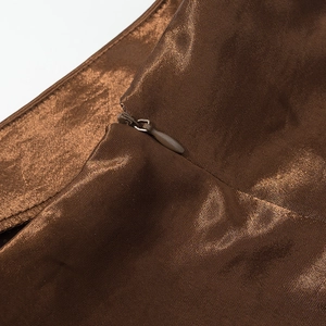 Dettaglio macro del tessuto in raso bronzo e cerniera invisibile sul vestito