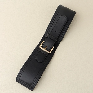 Detail of black wide elastic waist belt featuring a polished gold square buckle