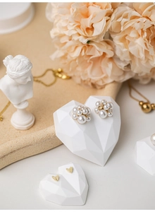 Close-up of pearl cluster earrings on a white heart-shaped jewelry display stand