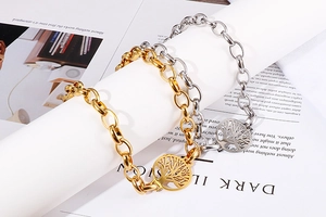 Dettaglio dei bracciali color oro e argento con ciondoli traforati albero della vita