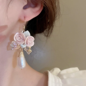 Close-up of model wearing pink ceramic rose earrings with waterdrop pearl pendants