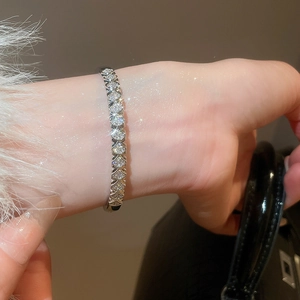Close-up of sparkling silver zircon pavé bangle bracelet on wrist with fur sleeve