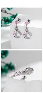 Detail view of crescent moon and pink heart stud earrings with cubic zirconia stones