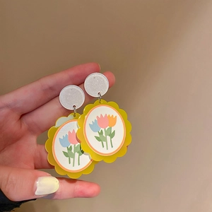 Détail de boucles d'oreilles en acrylique à motif tulipe et clous blancs à paillettes