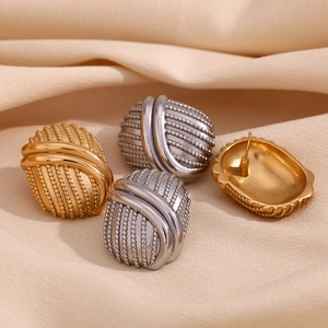 Dettaglio di orecchini ovali vintage in oro e argento su sfondo di seta liscia