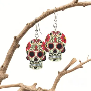 Macro detail of acrylic Day of the Dead skull earrings hanging on a rustic branch