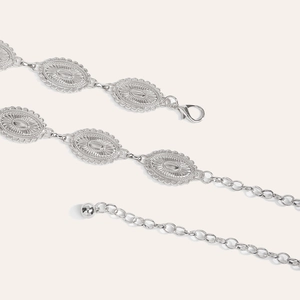 Macro detail of vintage silver metal waist chain with sunburst carved oval plates