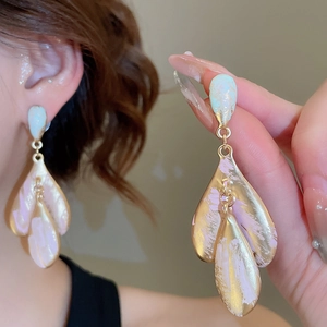 Close-up of gold heart earrings with pink and blue hand-painted petal details