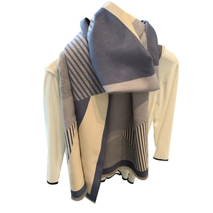 Knitted scarf with blue, grey, and beige geometric stripes draped over model shoulders